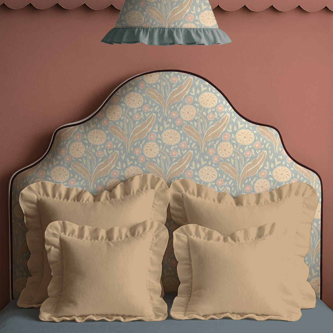 Decorative headboard with floral pattern and matching pillows against a pink wall.