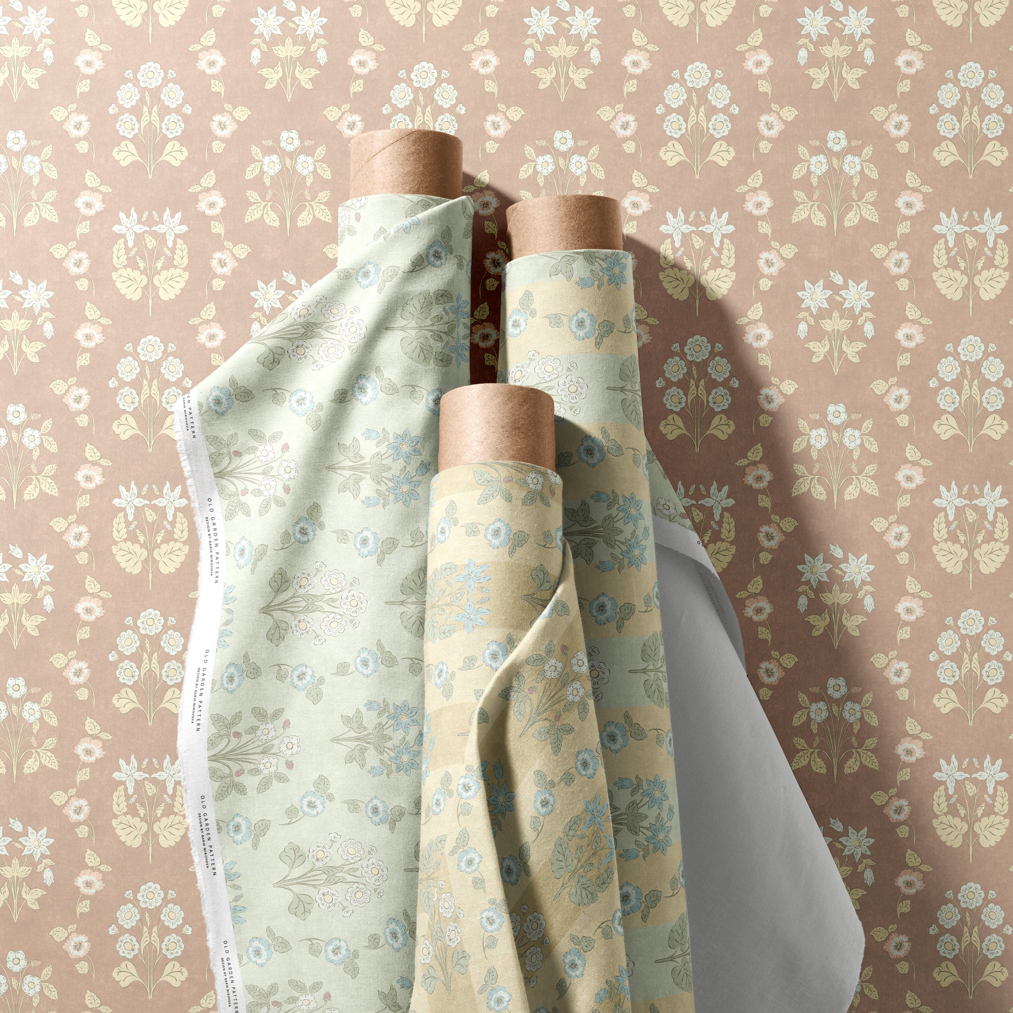 Rolls of fabric on wooden spools against a floral wallpapered wall.