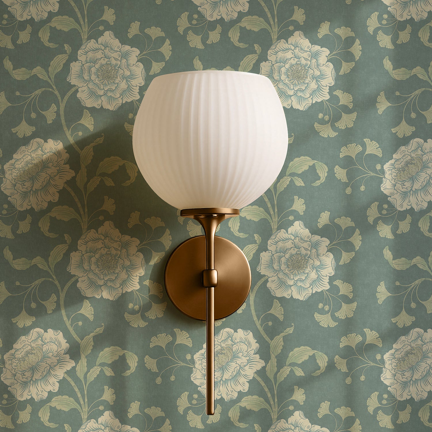 Wall sconce with white glass shade against floral wallpaper